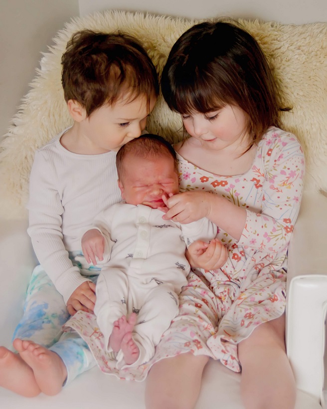 Two young children hold a newborn baby