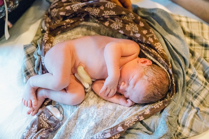 A sleeping baby lies upon a receiving blanket